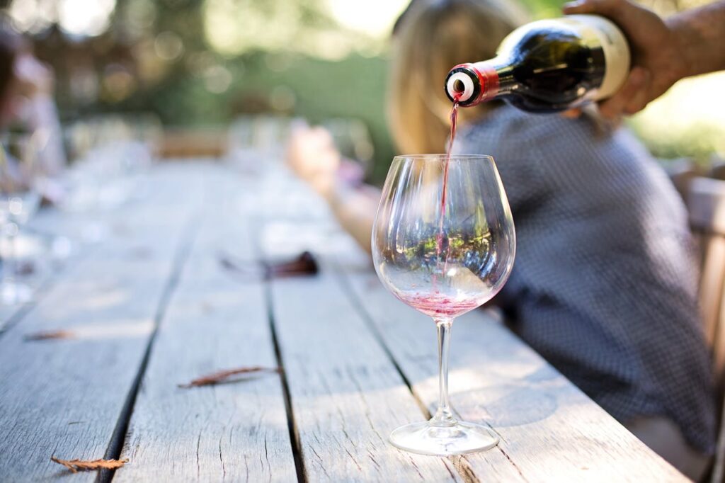 Taça de vinho com pessoa servindo o vinho.
