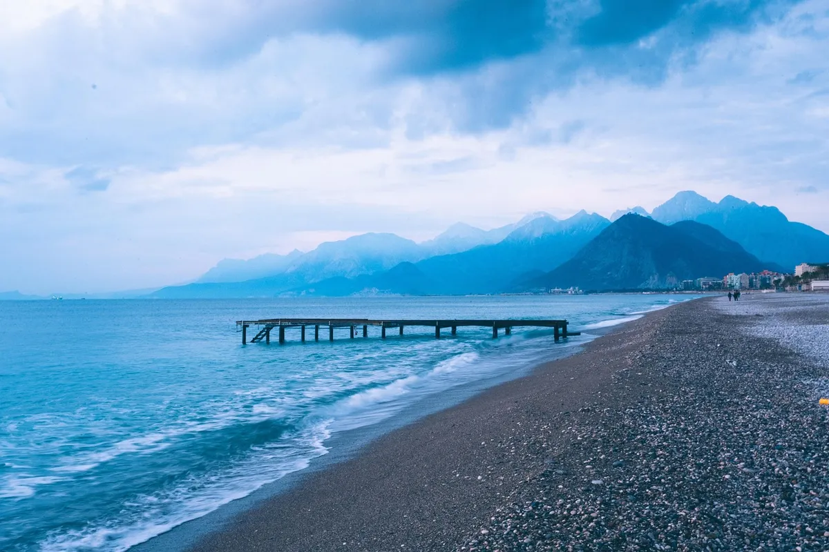 Praia de Konyaalti com mar azul e montanhas ao fundo em Antalya