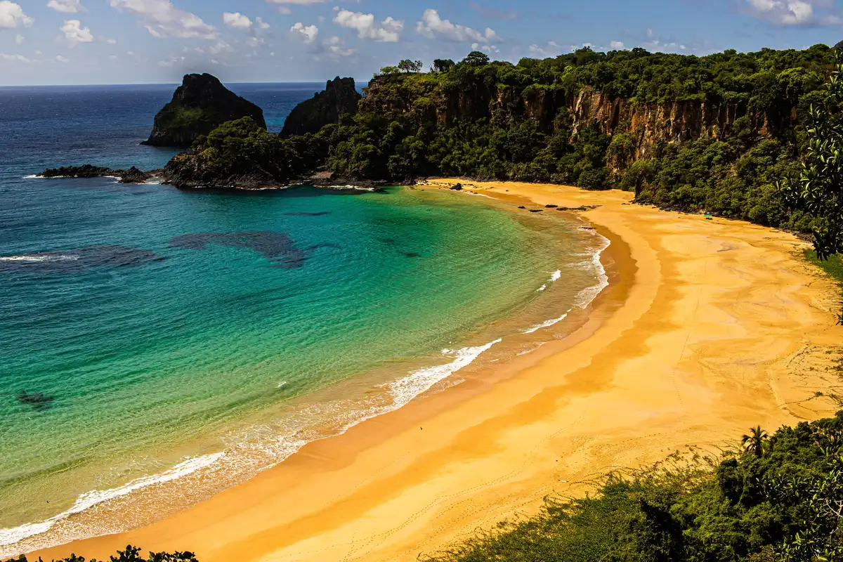 Vista aérea da Baía do Sancho, com falésias verdes e mar azul-turquesa