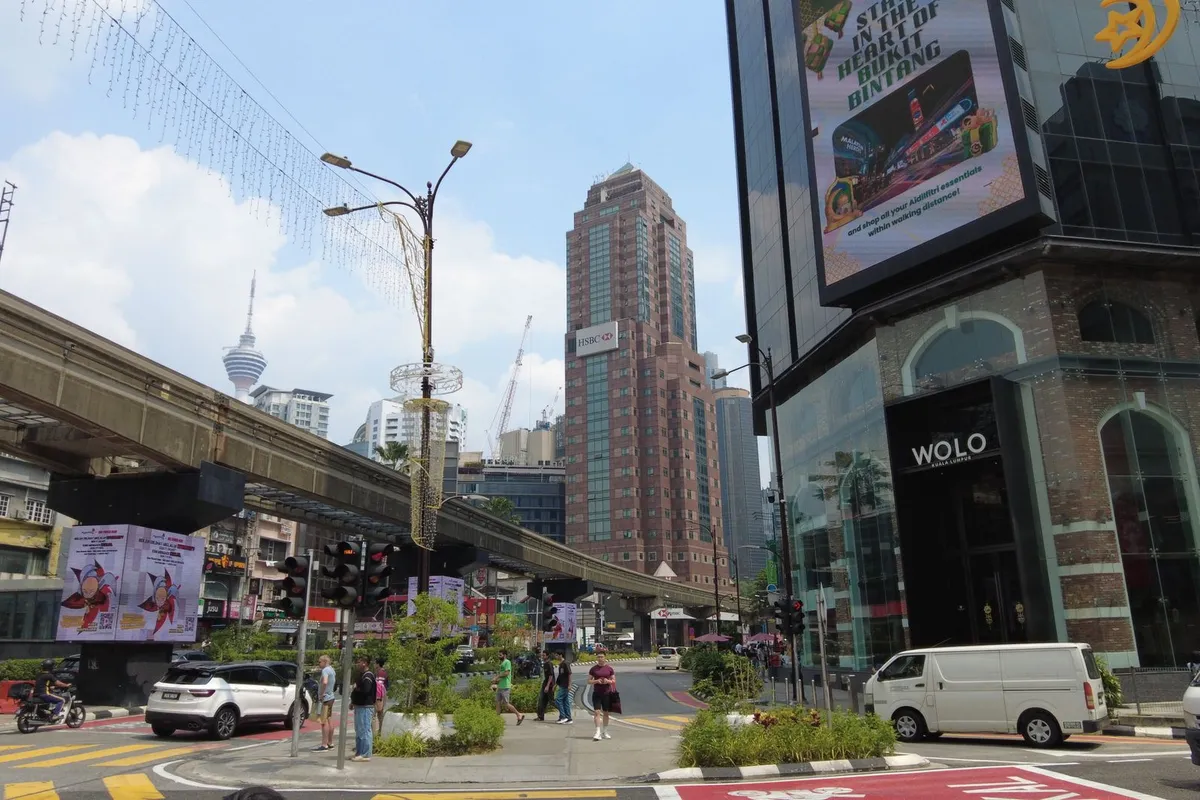 Rua movimentada em Bukit Bintang com letreiros e pessoas caminhando