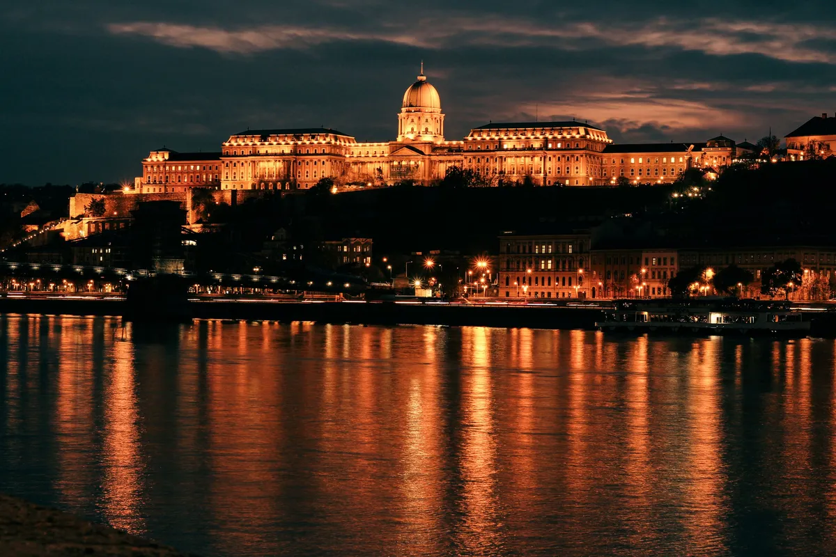 Castelo de Buda iluminado visto do rio Danúbio à noite em Budapeste