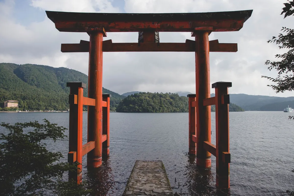 Torii vermelho do Santuário de Hakone no Lago Ashi com montanhas ao fundo