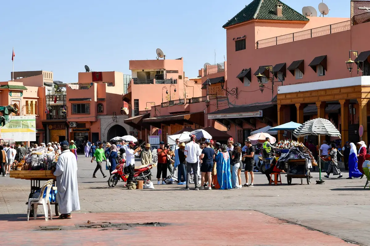 Praça Jemaa el-Fna em Marrakech com barracas e movimento intenso em fim de tarde.