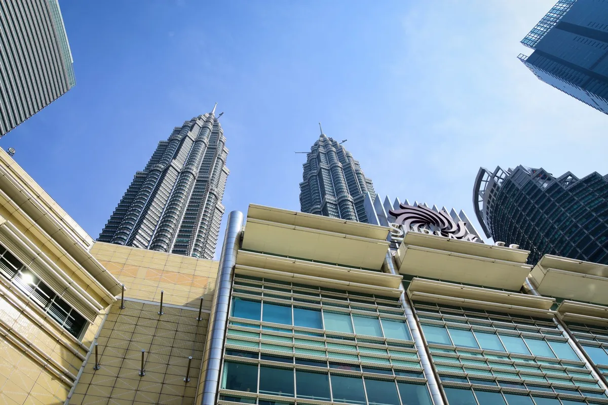 Torres Petronas iluminadas ao entardecer com skyline de Kuala Lumpur