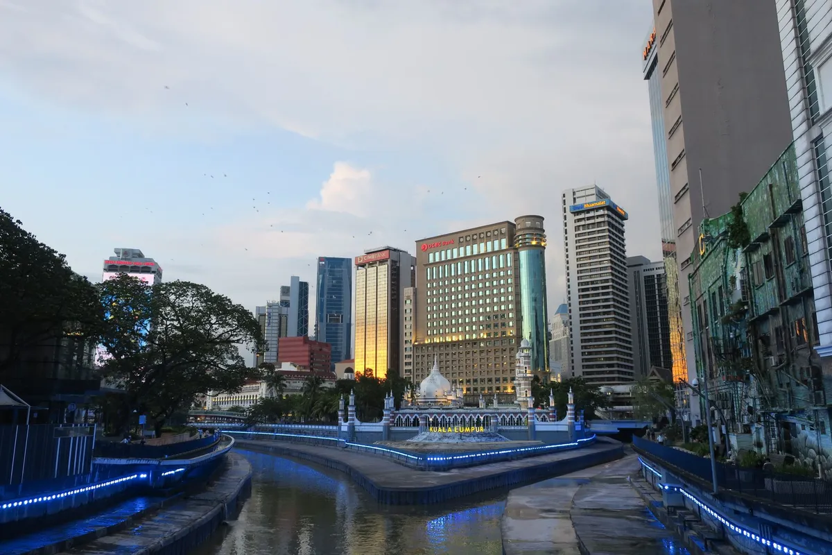Skyline de Kuala Lumpur ao pôr do sol com rio refletindo as luzes