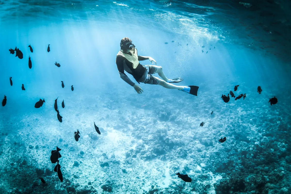 Pessoa fazendo snorkeling em água clara com máscara e snorkel