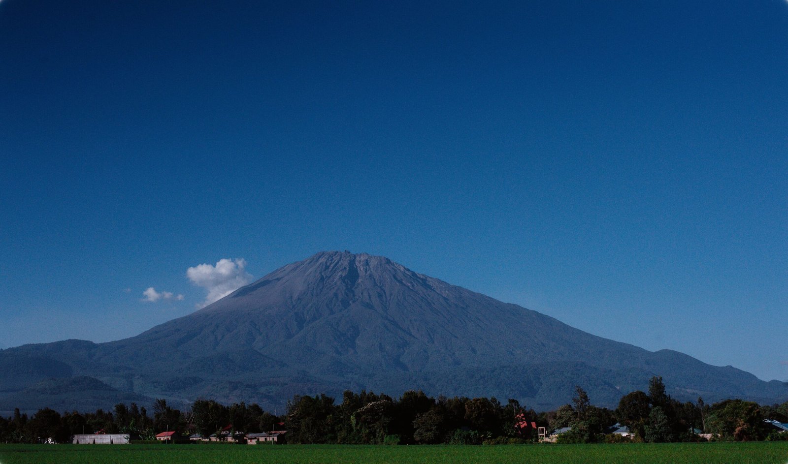 Monte Meru visto de um campo verde perto de Arusha, Tanzânia