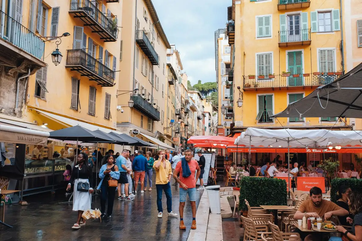 Rua estreita do Vieux Nice com predios coloridos e mesas nas calçadas