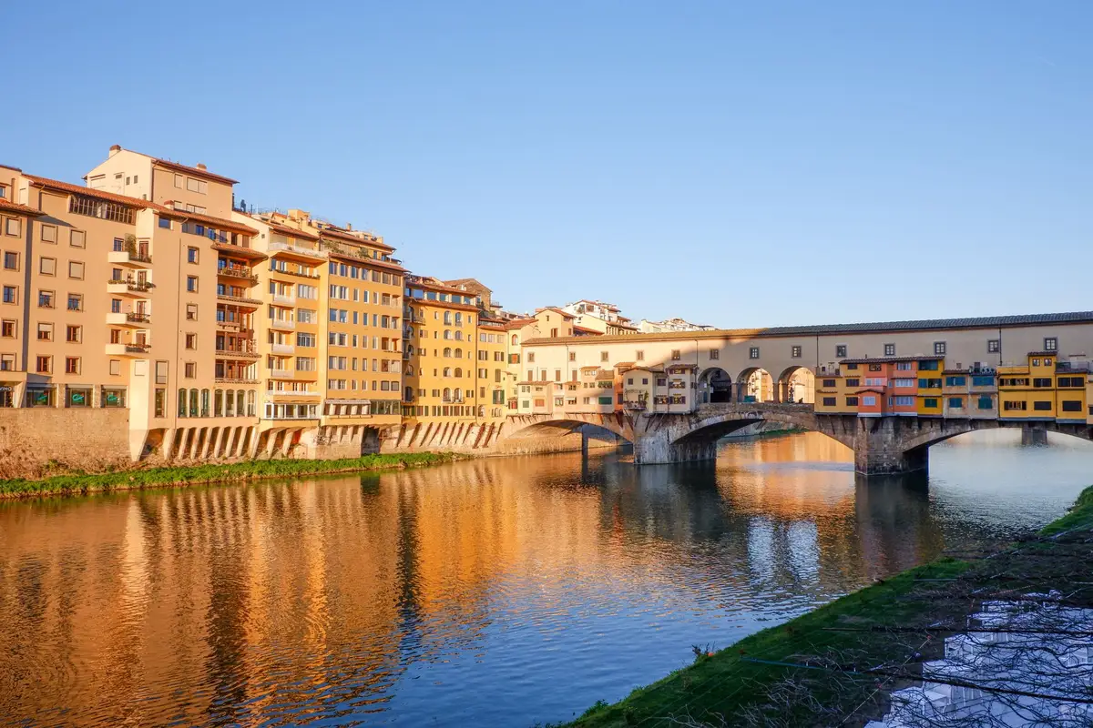 Ponte Vecchio refletida no rio Arno ao entardecer em Florença