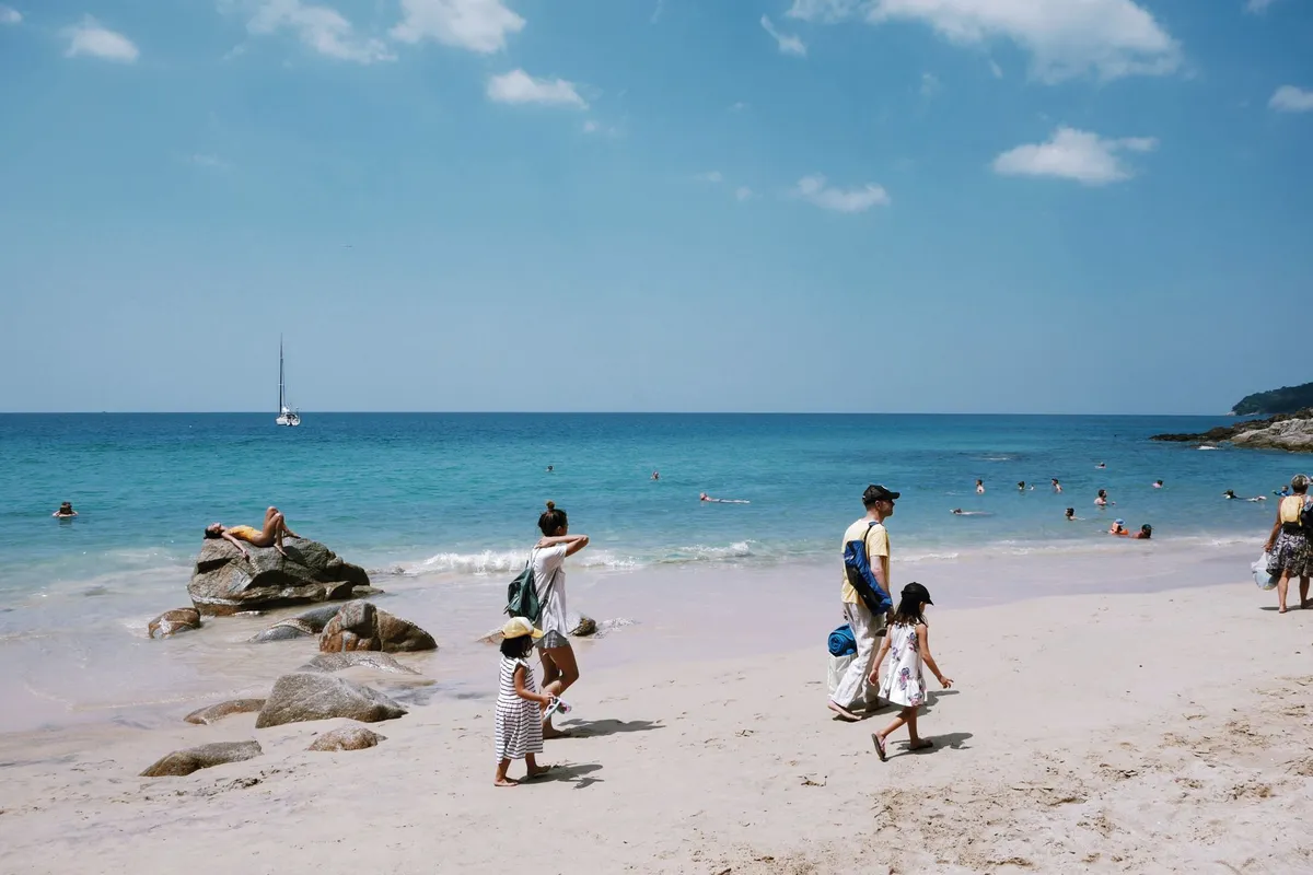 Famílias na areia de uma praia de águas calmas e claras
