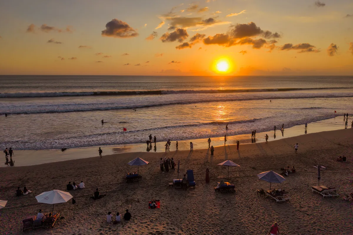 Pôr do sol na praia de Kuta em Bali com pessoas na areia