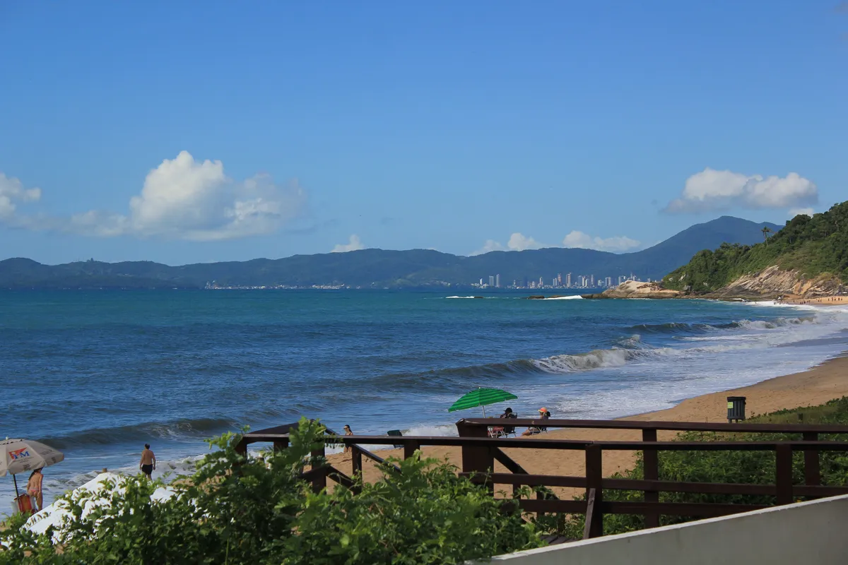 Praia com ondas e skyline de Balneário Camboriú ao fundo