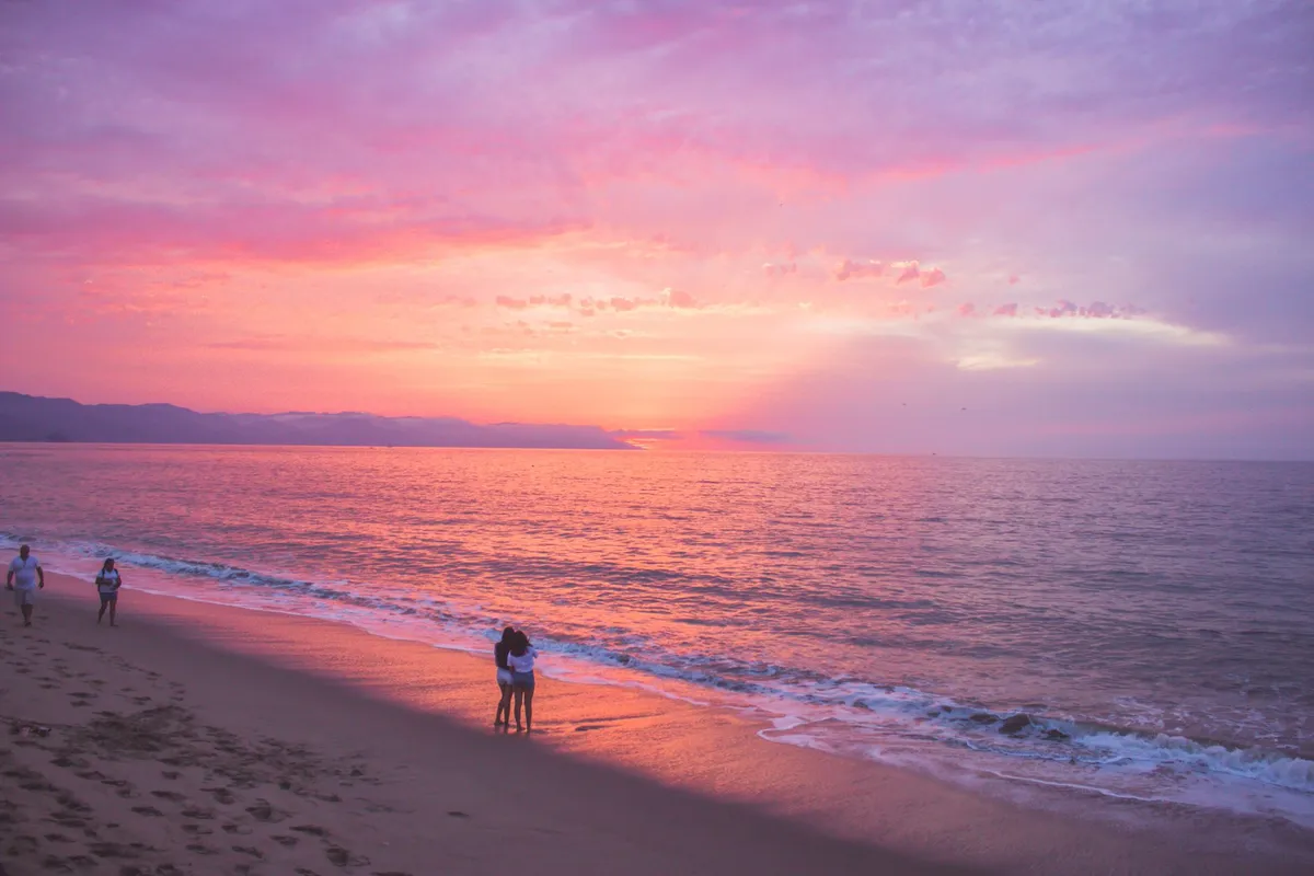 Pessoas na praia durante o pôr do sol em Puerto Vallarta