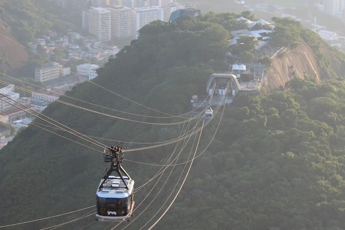 Cabine de teleférico sobre paisagem litorânea de montanha e mar