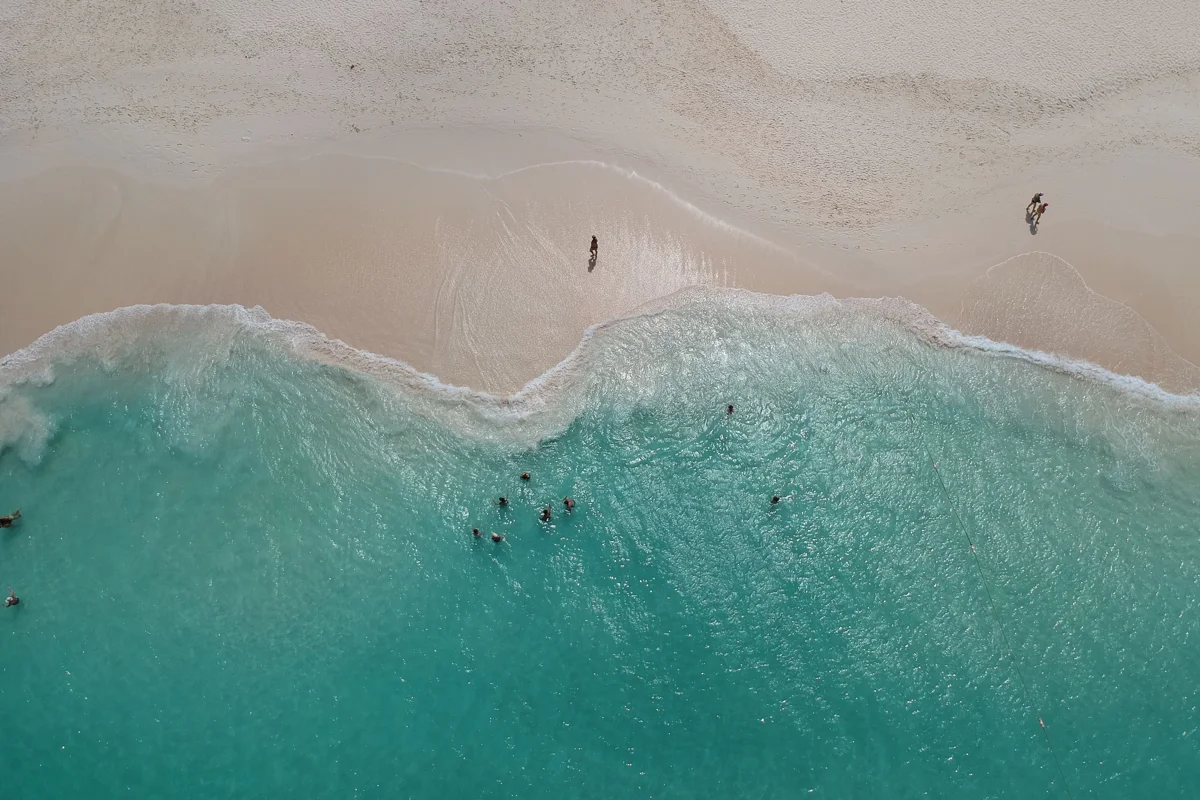Vista aérea de ondas quebrando em praia de areia clara no Caribe