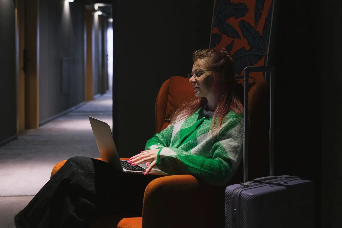 Mulher trabalhando no laptop em corredor de hotel durante viagem de bleisure