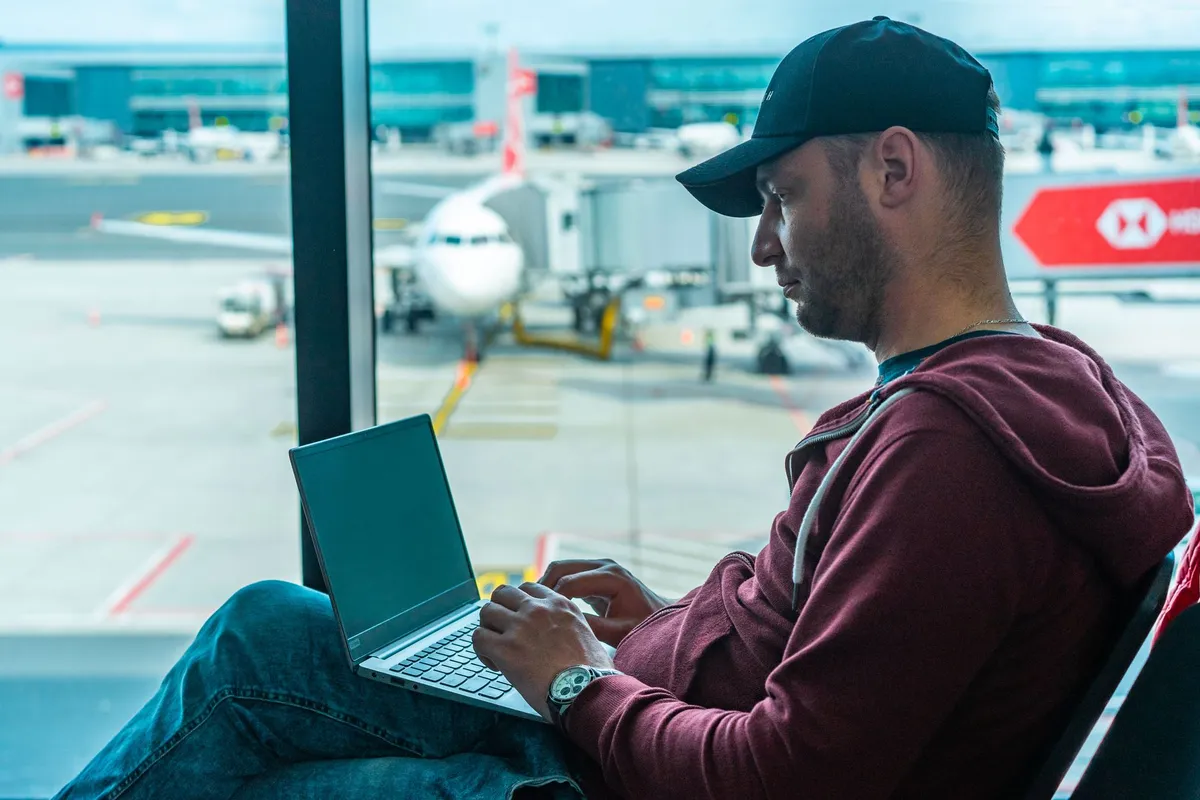 Homem trabalhando no laptop em sala de embarque do aeroporto