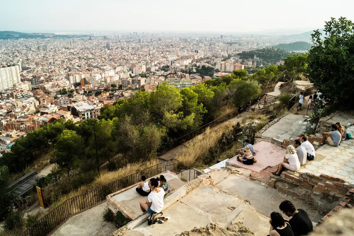 Pessoas sentadas no mirante dos Bunkers del Carmel observando a cidade