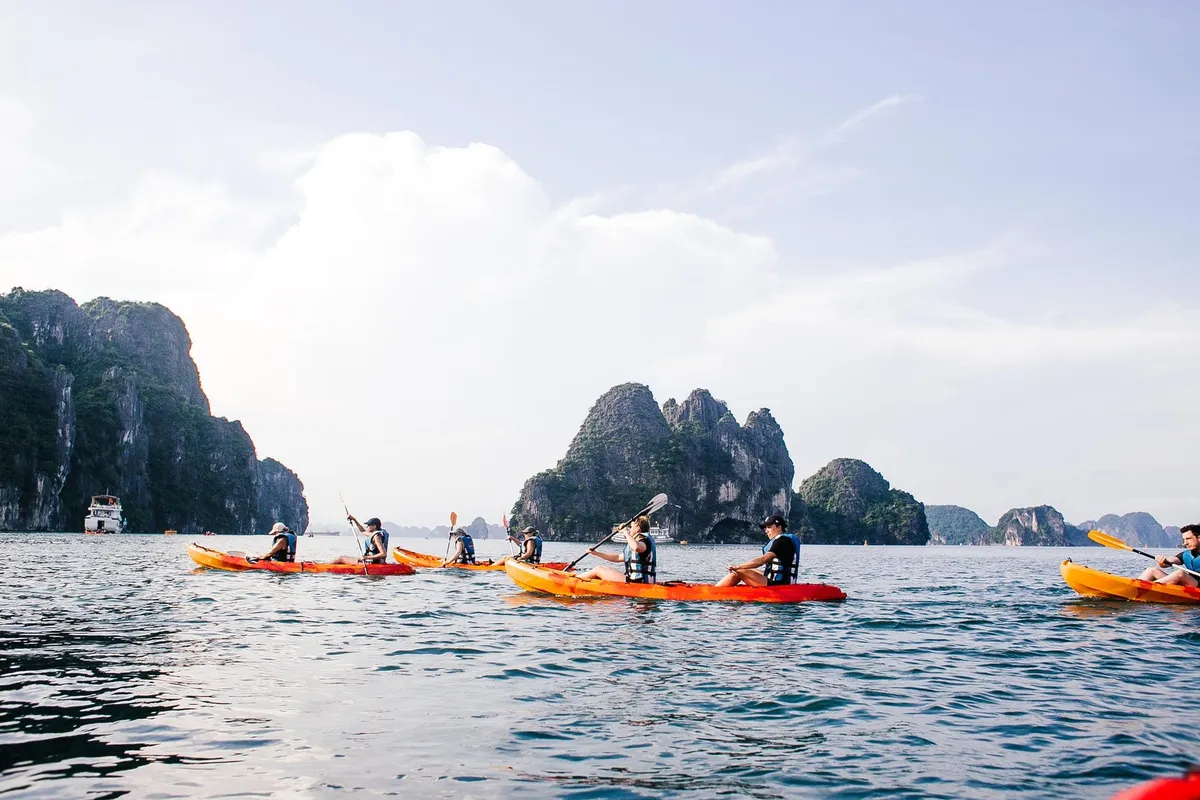 Pessoas de caiaque entre as ilhas de calcário da Baía de Ha Long