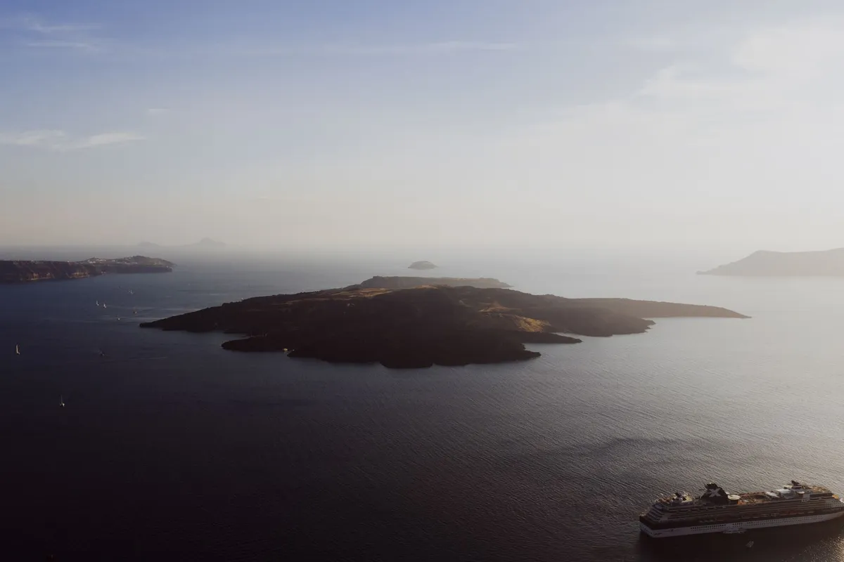 Vista aérea da Caldeira de Santorini com barcos navegando entre as falésias