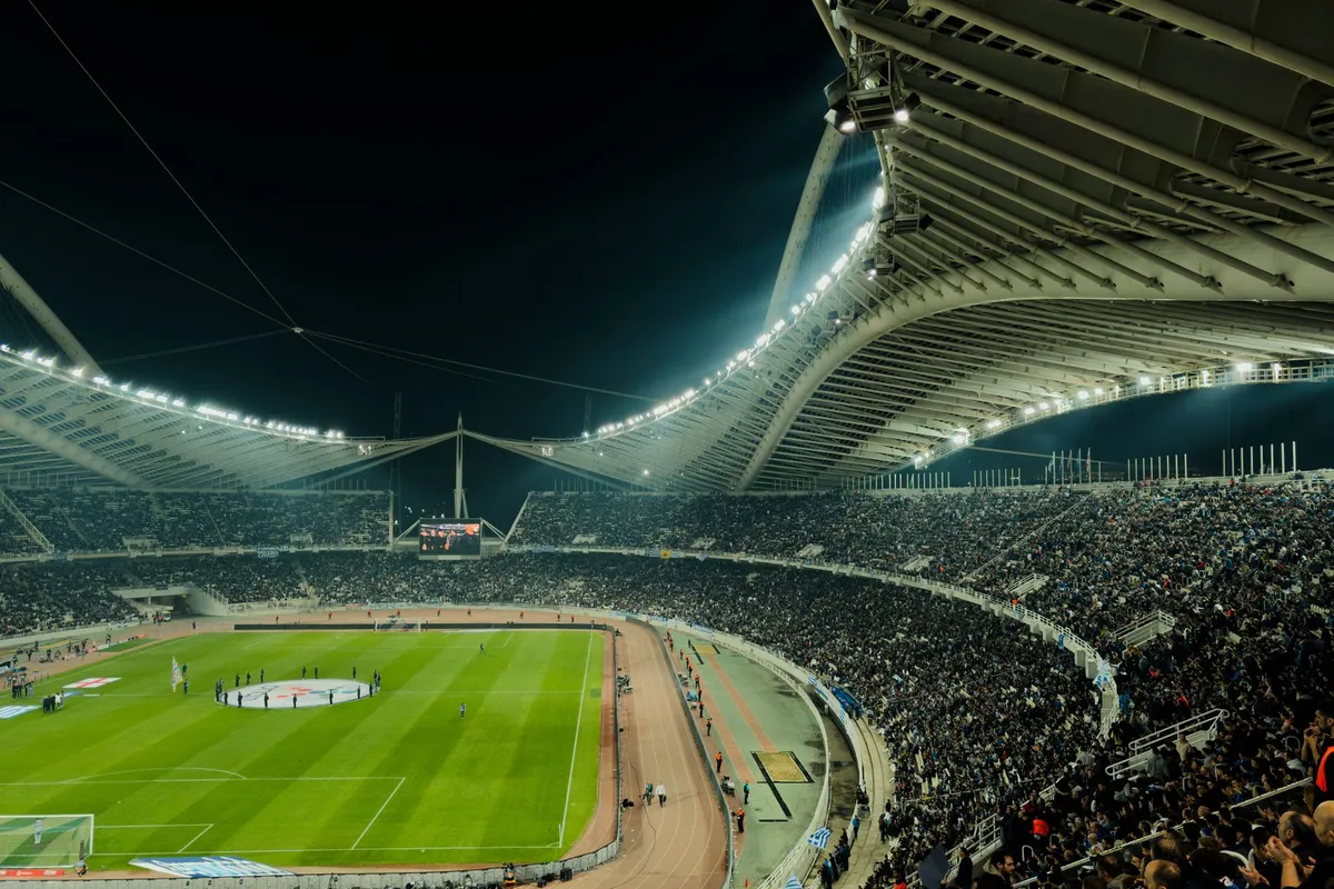 Estádio de futebol iluminado à noite com torcida