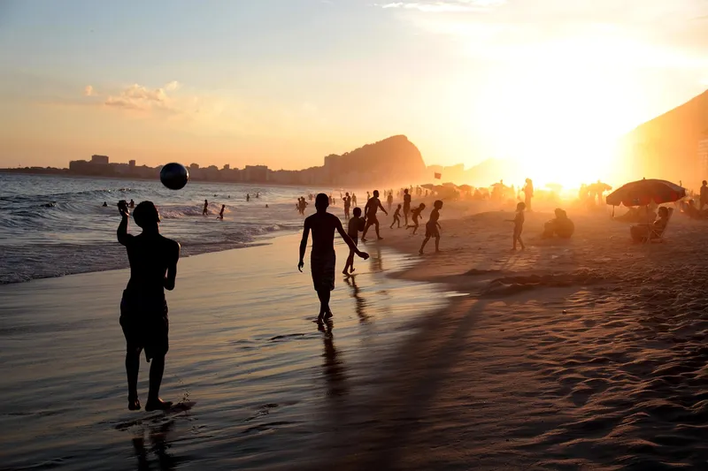 Pessoas na faixa de areia de uma praia carioca