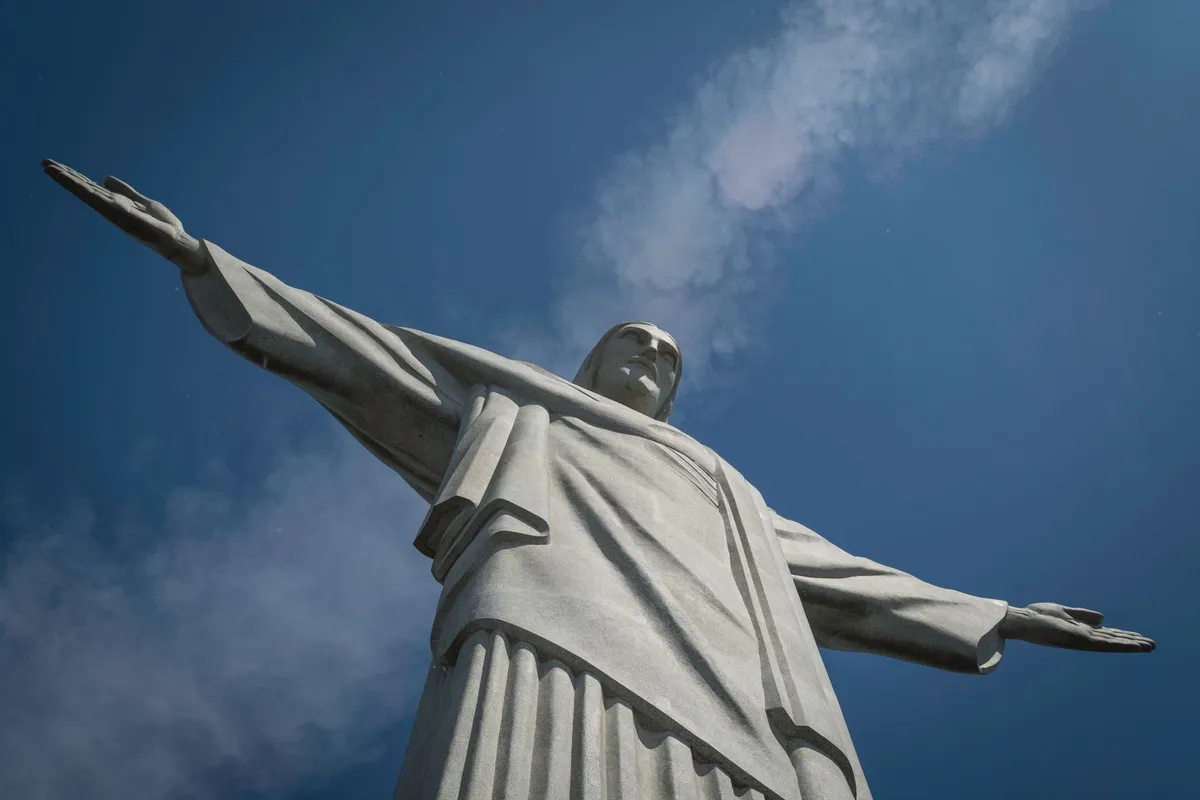Estátua do Cristo Redentor de braços abertos sob céu azul