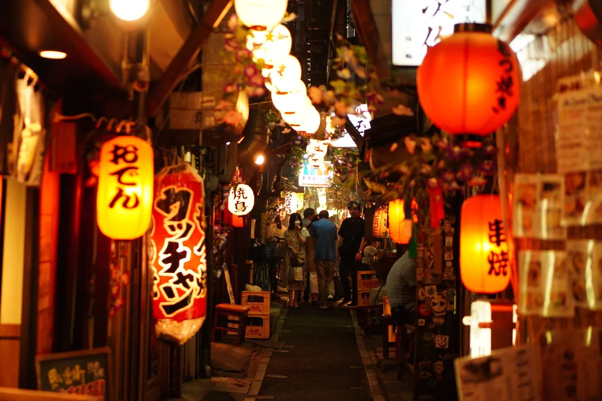 Beco estreito do Golden Gai em Shinjuku iluminado por lanternas de papel à noite