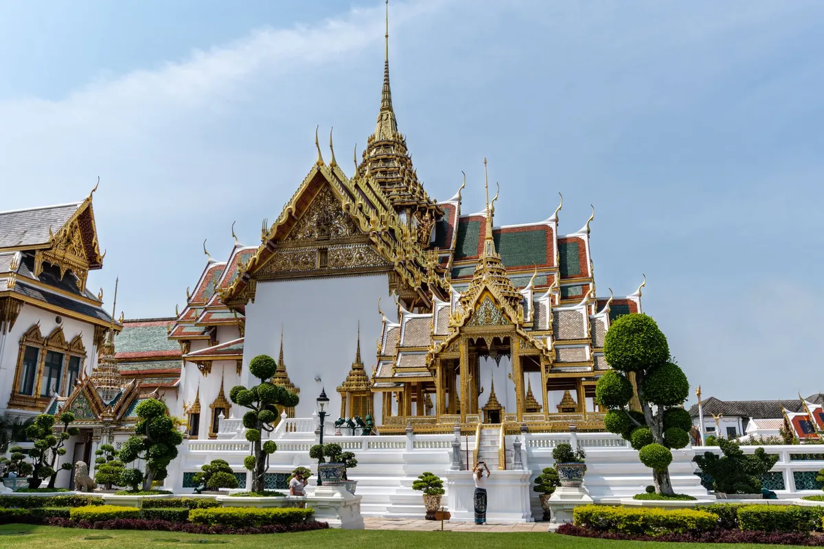 Fachada dourada do Grande Palácio de Bangkok com torres e telhados ornamentados