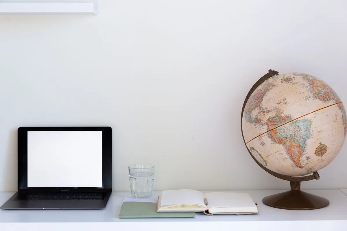 Mapa-múndi na parede e notebook aberto sobre a mesa
