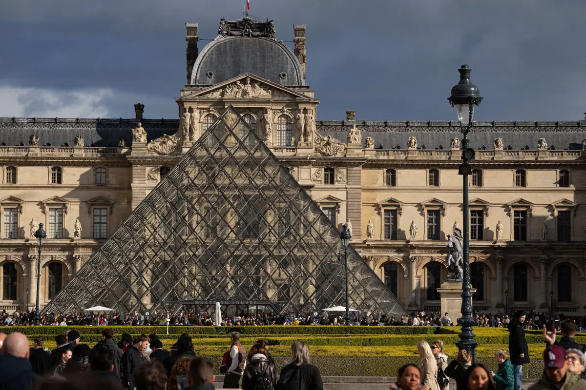 Visitantes frente a la pirámide del Louvre en París