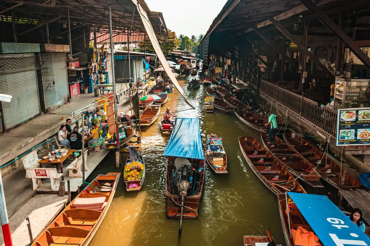 Canal estreito do mercado flutuante nos arredores de Bangkok com barco a remo