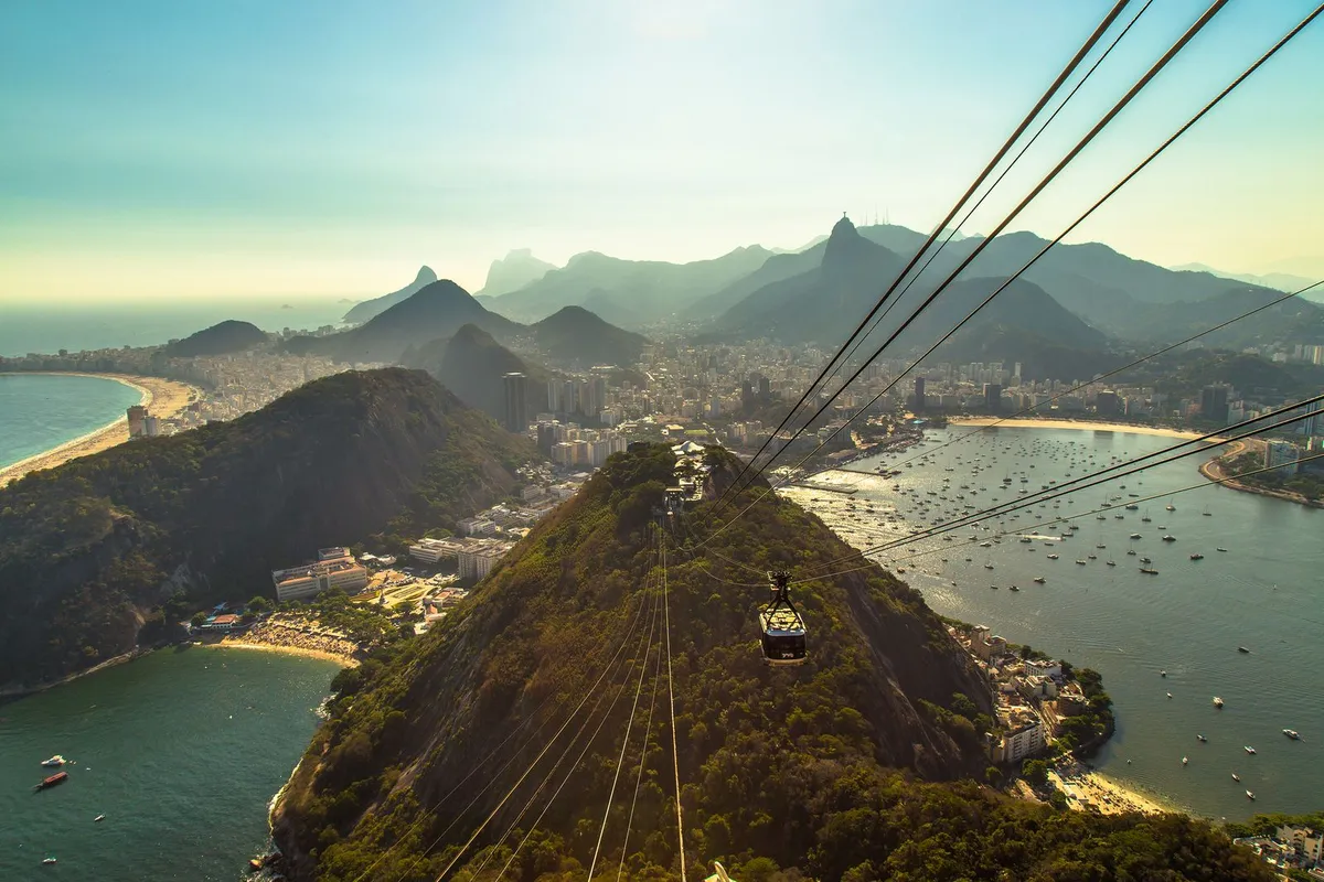 Bondinho do Pão de Açúcar subindo com a Baía de Guanabara ao fundo, no Rio de Janeiro