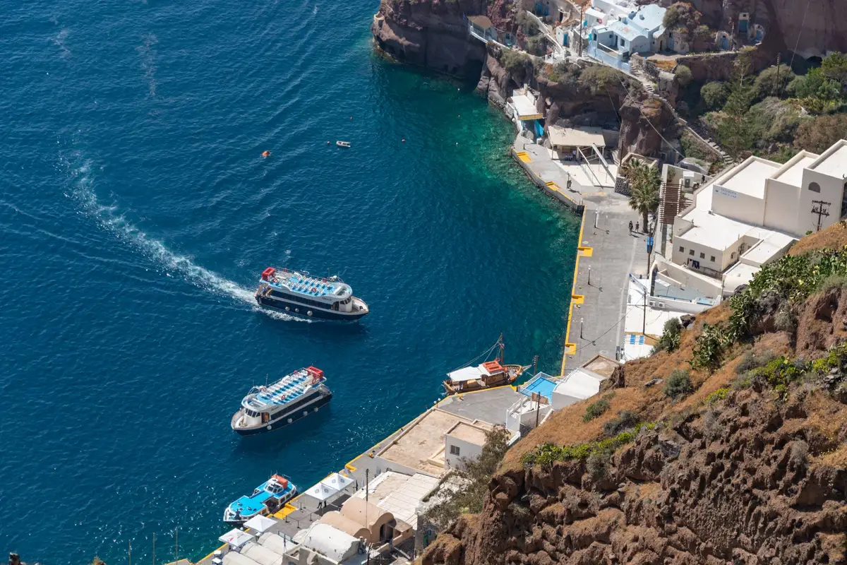 Porto antigo de Fira com barcos e escadaria na falésia de Santorini
