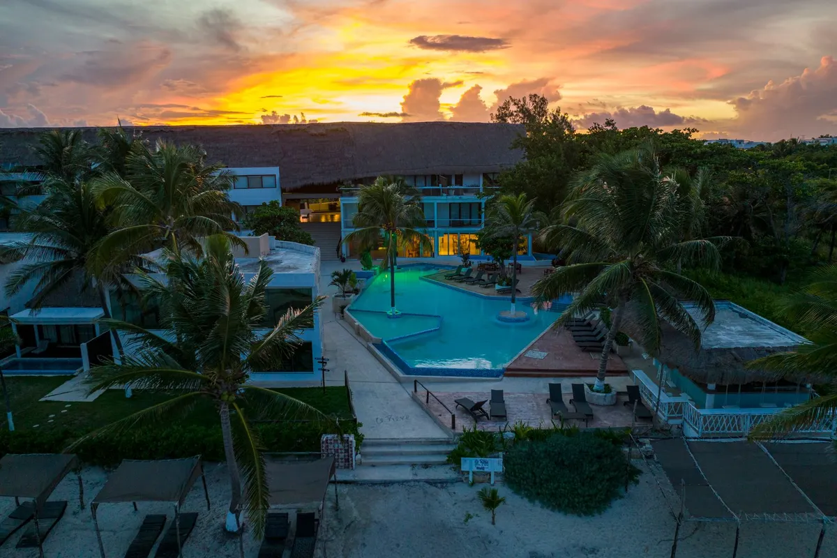 pôr do sol sobre piscina e praia de resort no Caribe