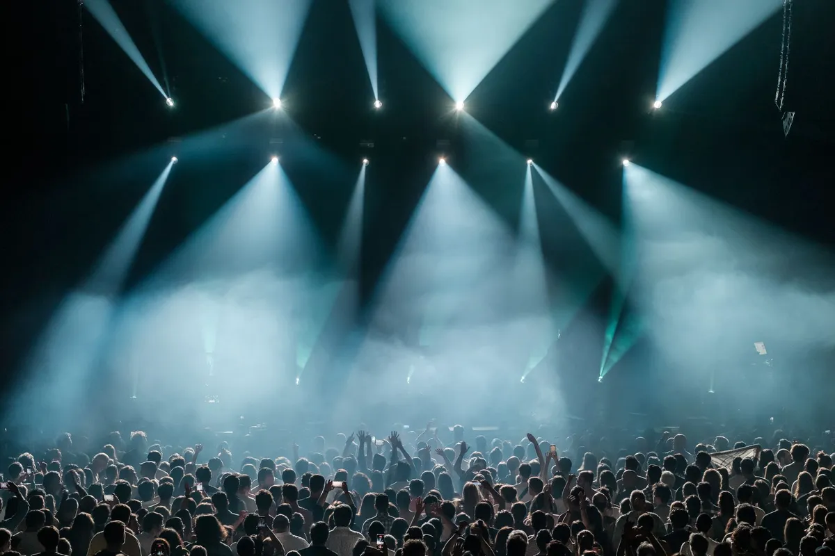Multidão de show sob luzes de palco em tons vibrantes