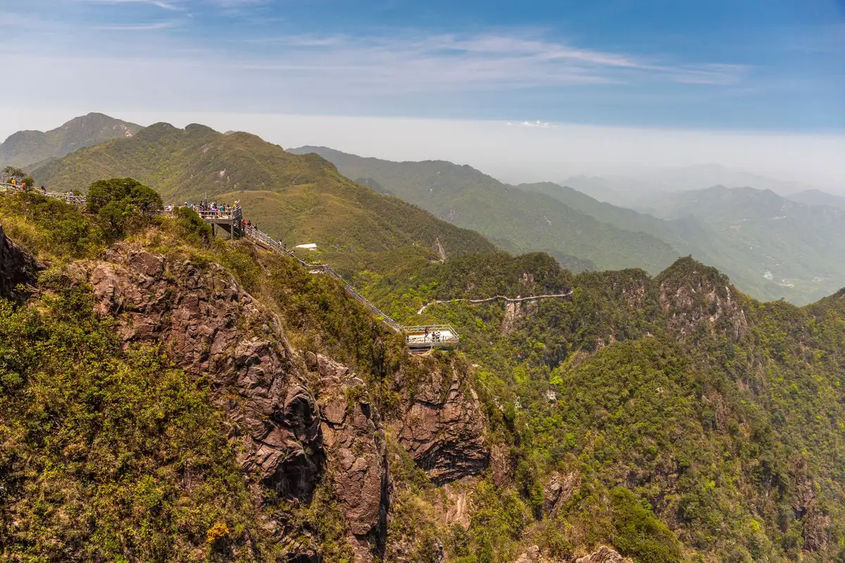 Turistas observando a paisagem do alto de um mirante de montanha, cenário semelhante ao mirante da Serra do Corvo Branco