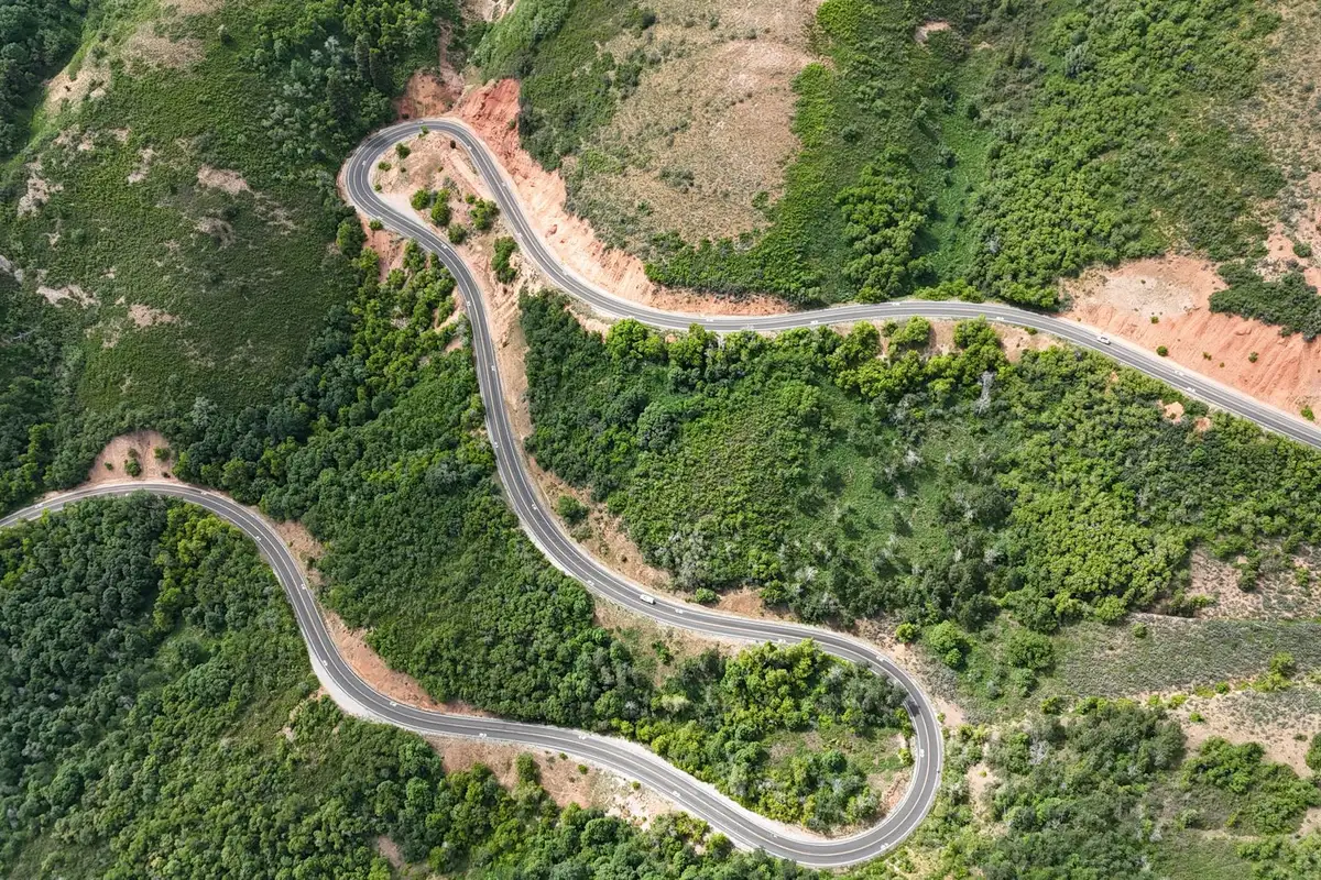 Vista aérea de estrada sinuosa em meio a montanhas verdes, semelhante ao traçado da Serra do Rio do Rastro