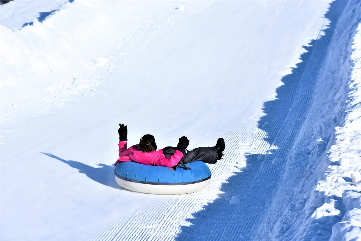Pessoas descendo tobogã de neve, atração parecida com o tubing do Snowland