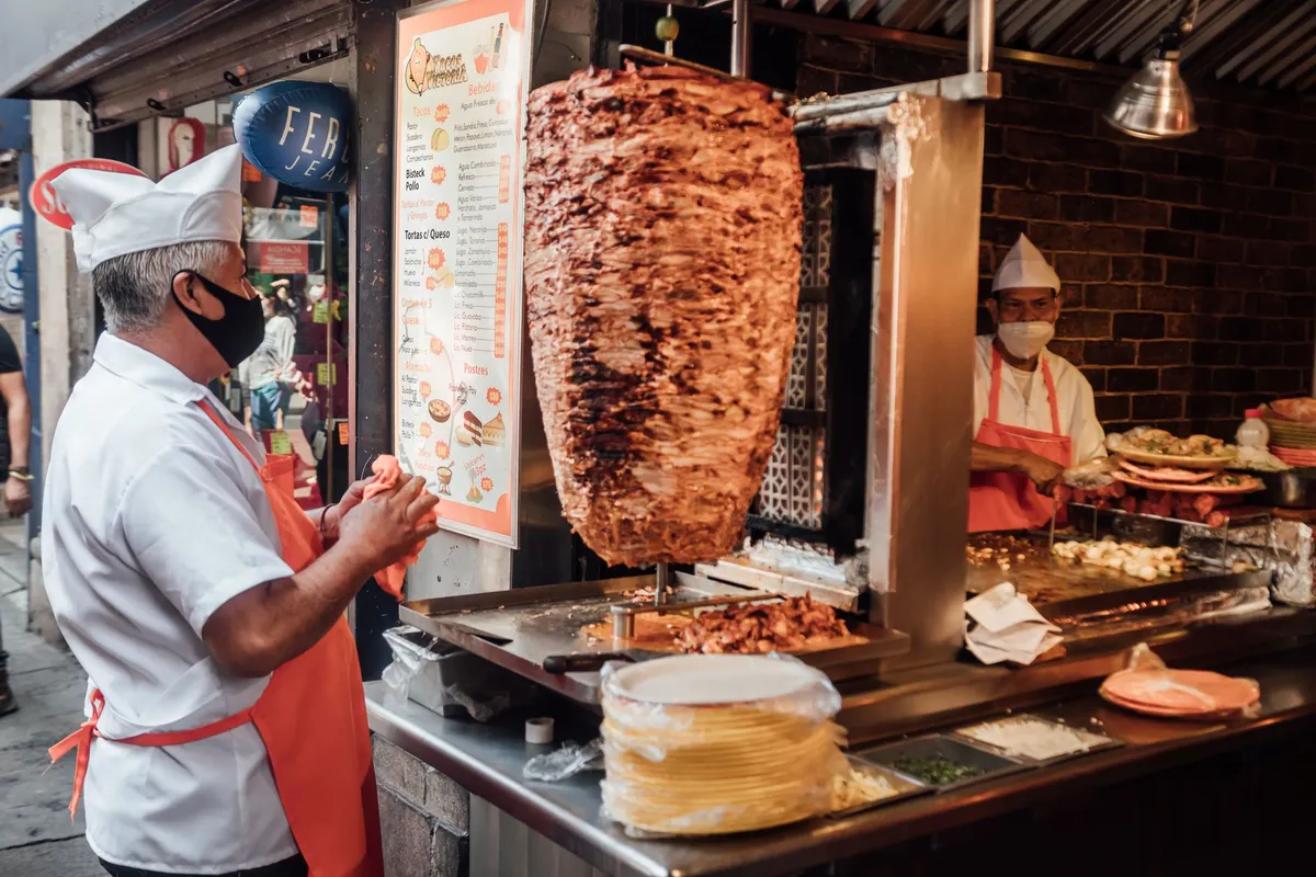 Taqueiro preparando tacos al pastor no trompo em banca de rua na Cidade do México