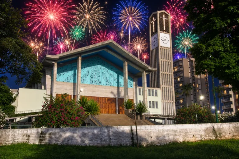 Igreja Matriz São João Batista em Olímpia à noite com torre do relógio e céu cheio de fogos coloridos