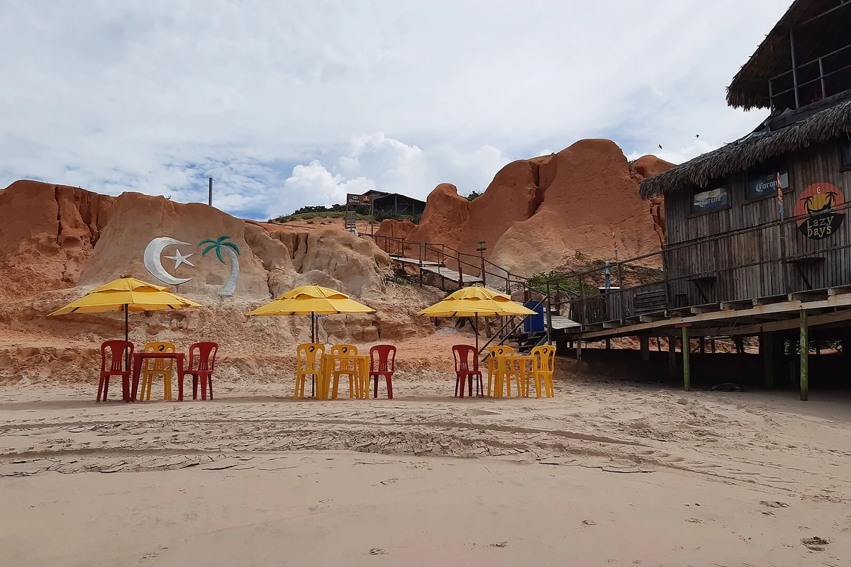 Falésias de Canoa Quebrada com pintura de meia-lua, estrela e coqueiro junto a barracas de praia