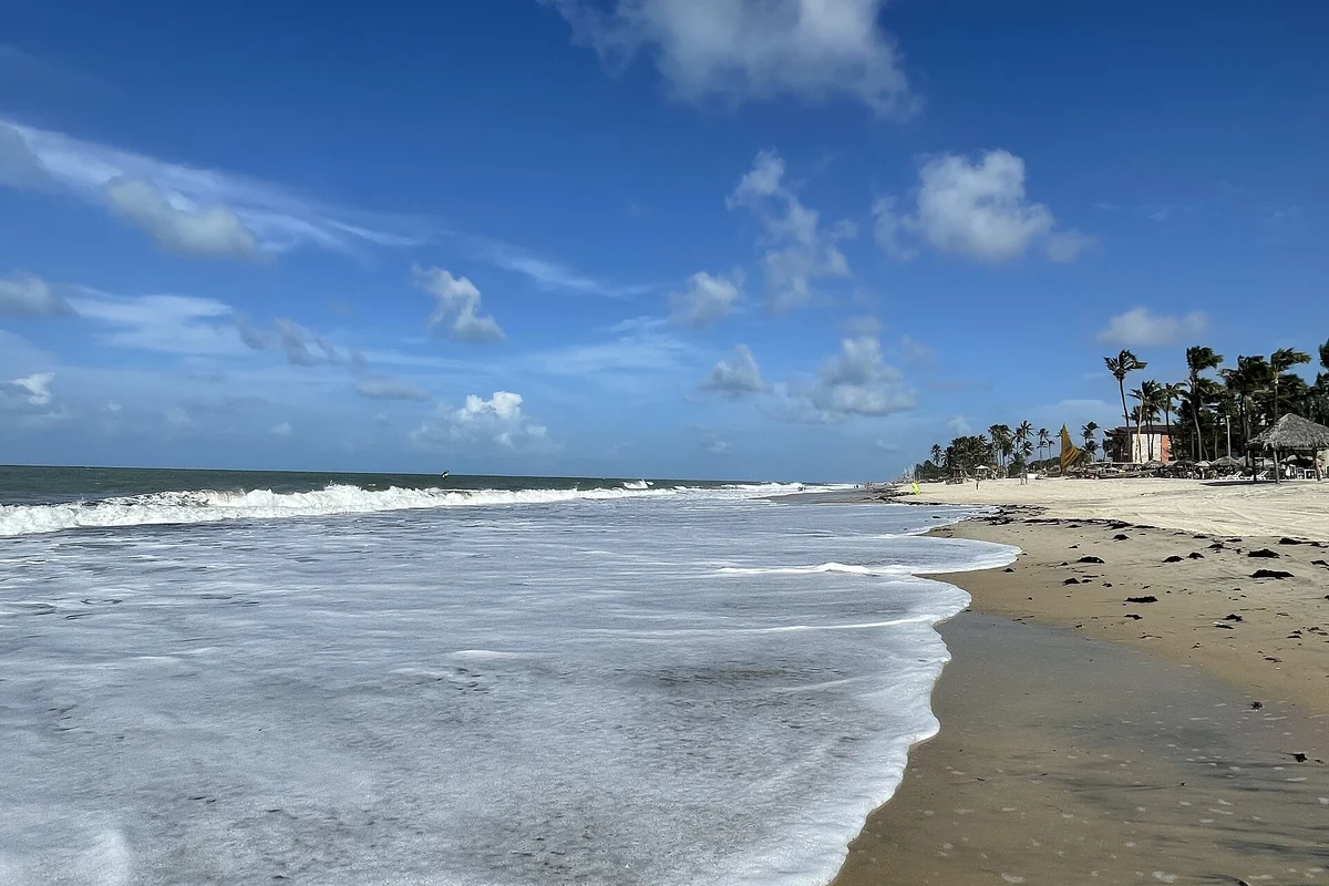 Praia de Cumbuco com faixa de areia, mar e coqueiros