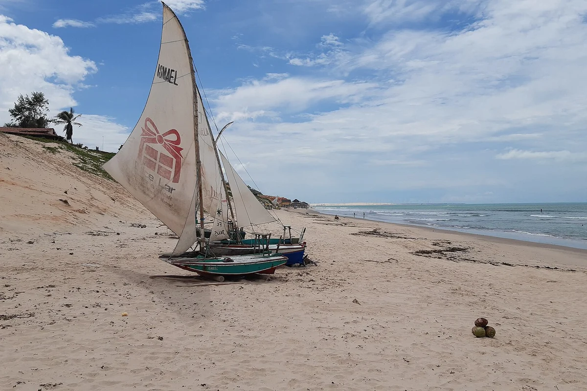 Jangada na faixa de areia da praia de Canoa Quebrada diante das falésias