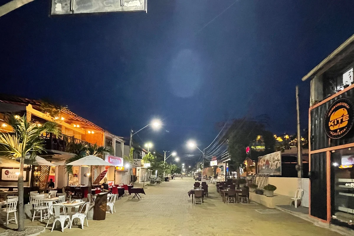 Rua do centro da vila de Cumbuco à noite, com restaurantes e iluminação