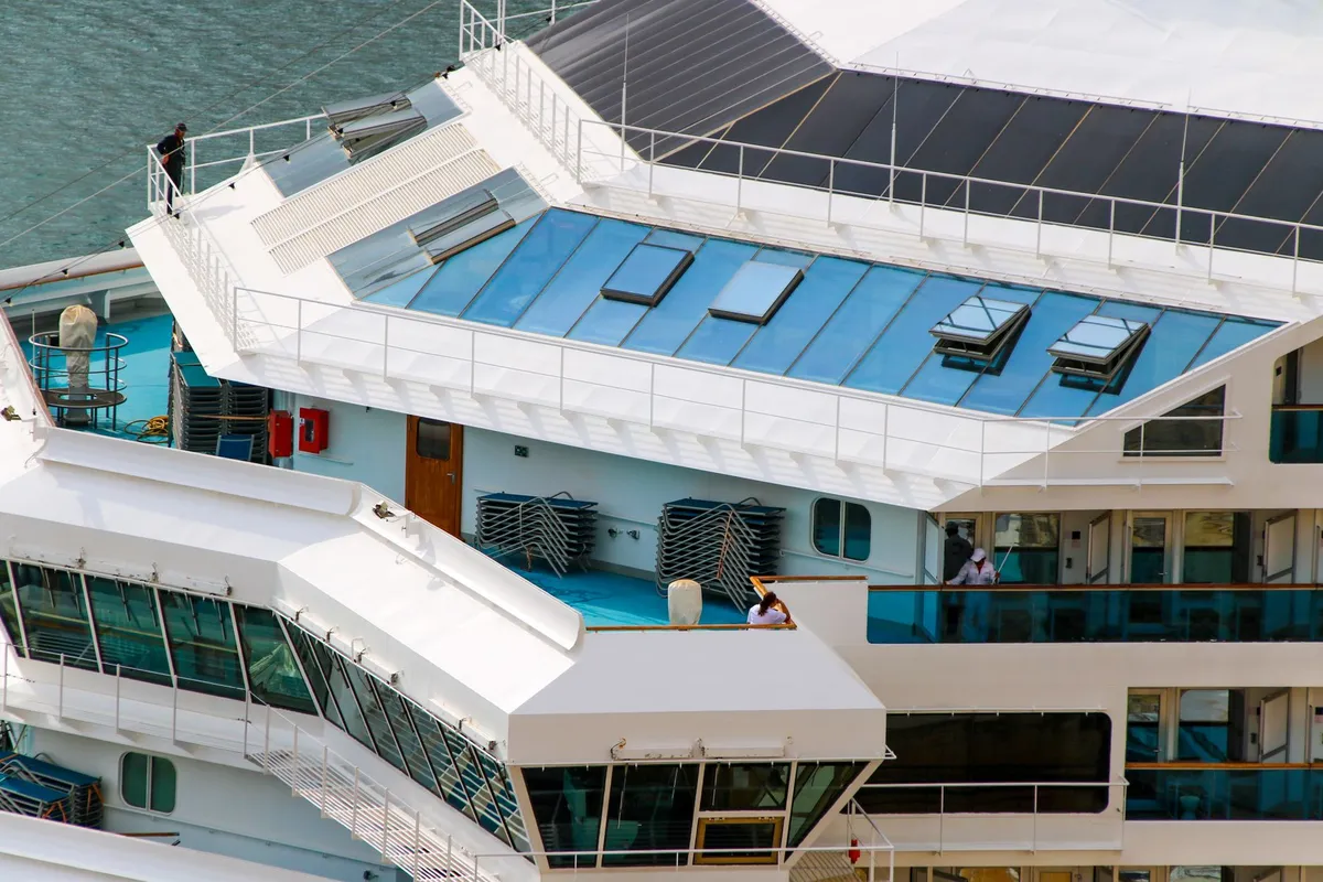 Deck de navio de cruzeiro com piscinas e espreguiçadeiras visto de cima