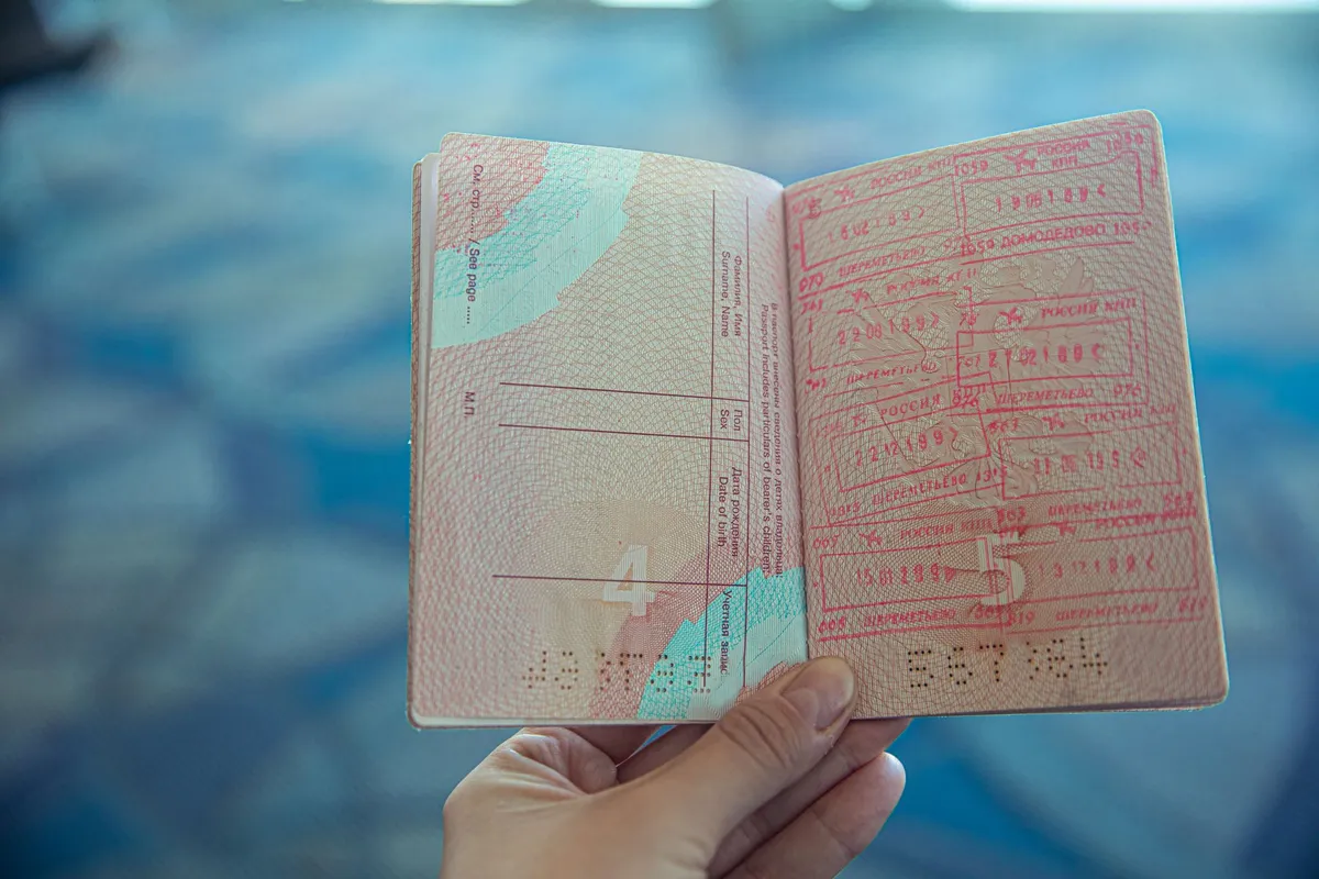 Passaporte aberto com páginas cheias de carimbos de entrada e saída