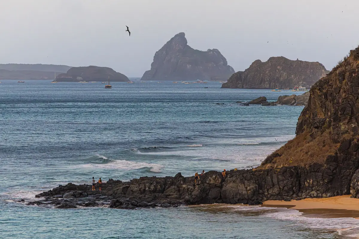 Vista aérea do mar azul de Fernando de Noronha com o Morro Dois Irmãos ao fundo