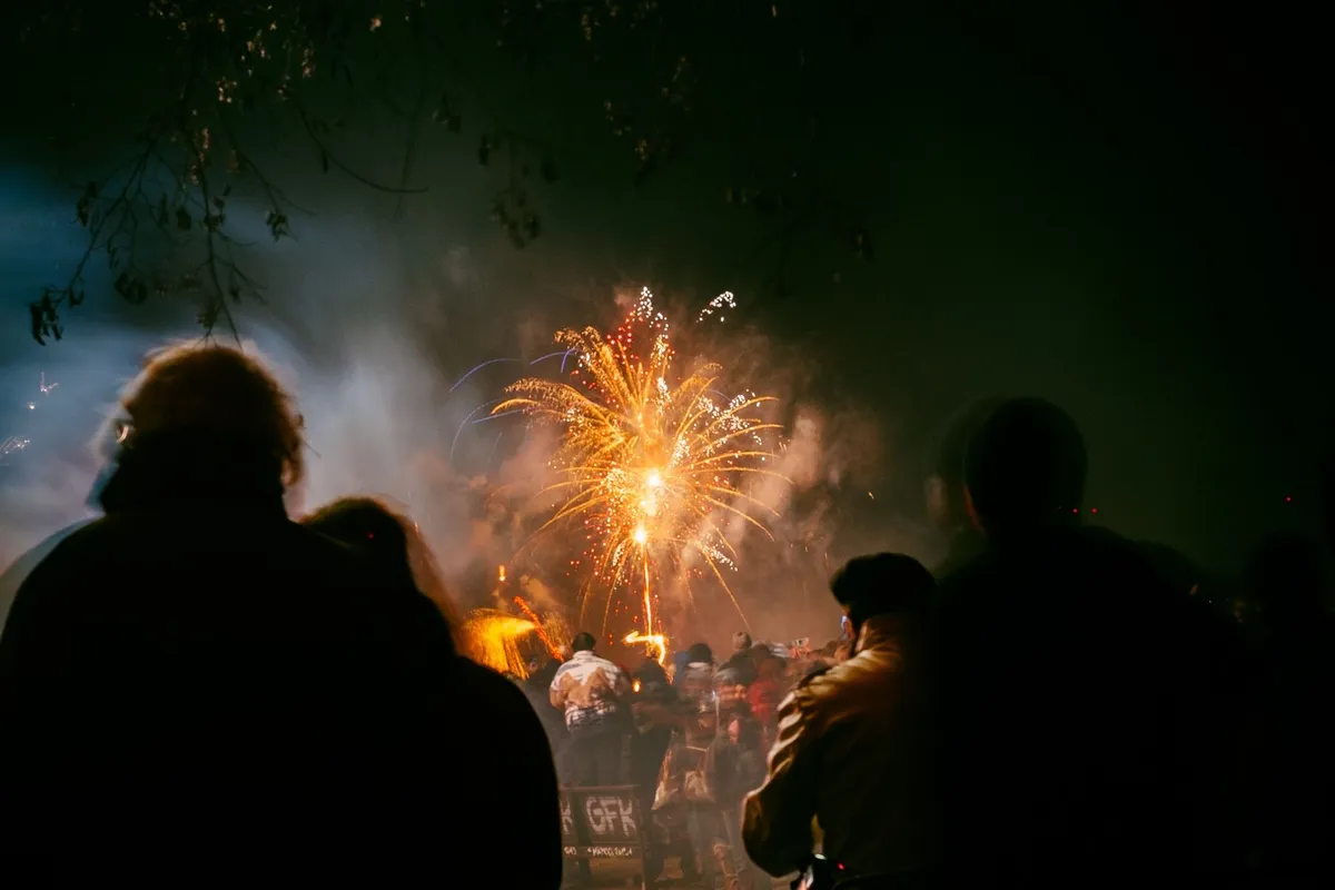 Multidão assistindo à queima de fogos de réveillon em um mirante à beira-mar