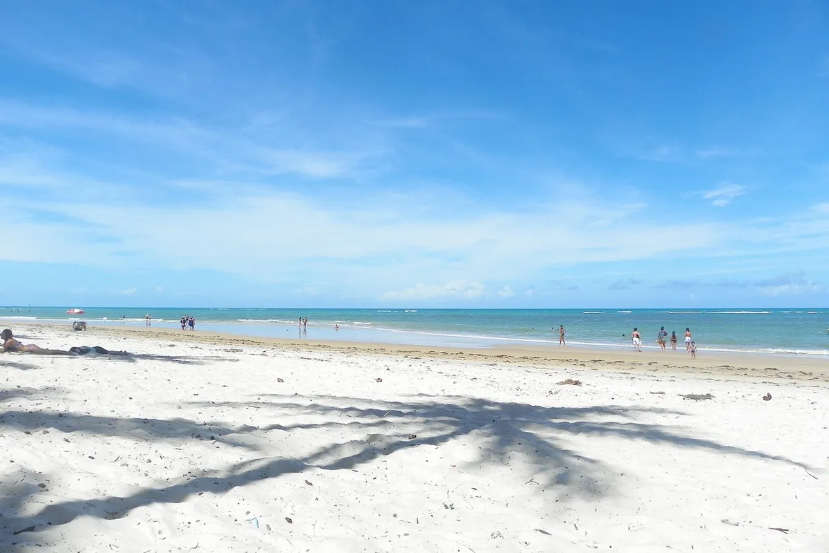 Praia de Arraial d'Ajuda durante o dia, com areia e mar